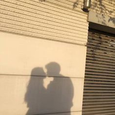 a shadow of a person holding a cell phone in front of a building with shutters