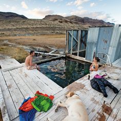 two people and a dog sitting on a dock