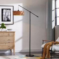 a living room with a chair, lamp and pictures hanging on the wall above it