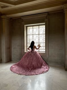 a woman in a pink dress is looking out the window