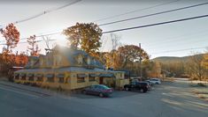 the sun shines brightly in front of a small yellow building with cars parked outside