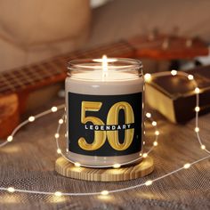 a candle with the number 50 on it sitting next to some string lights and a guitar