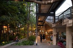 people are walking through an open area with trees and plants on the sides of it