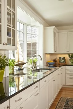 a kitchen with white cabinets and black counter tops