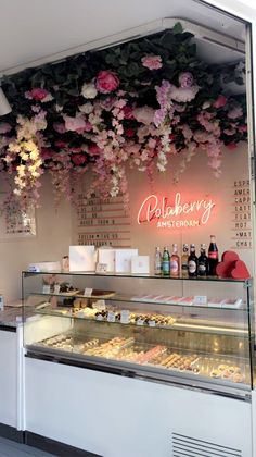 a bakery with flowers hanging from the ceiling and food on display in front of it