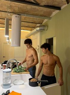 two shirtless men are preparing food in the kitchen