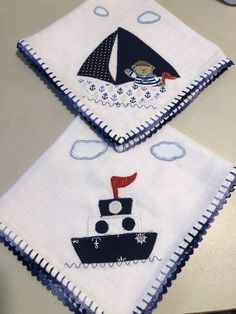 two napkins with sailboats on them sitting on a table