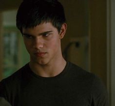 a young man in a black shirt looking at the camera with an intense look on his face