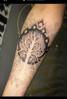 a person with a tattoo on their arm that has an image of a tree in the middle