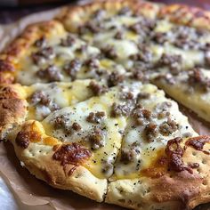 a pizza with cheese and sausage on it is sitting on a piece of parchment paper