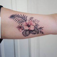 a woman's arm with flowers and leaves on it