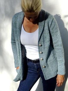 a woman standing against a wall with her hands in her pockets