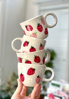 a stack of four coffee cups with strawberries on them