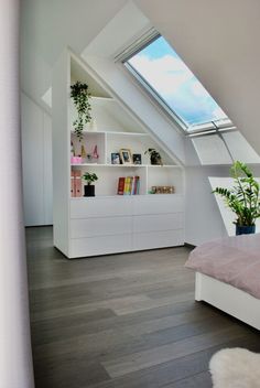 an attic bedroom with skylight and bookshelf