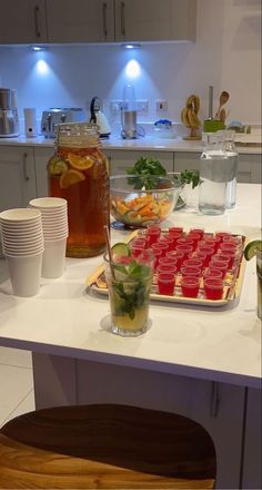 a kitchen counter topped with plates and cups filled with food next to drinks on top of it