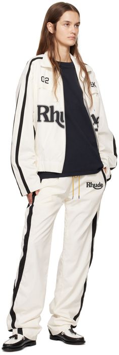 Polyester duck canvas track jacket. · Paneled construction · Funnel neck · Two-way zip closure · Text and logo printed at front · Welt and seam pockets · Elasticized hem · Dropped shoulders · Stripes at sleeves · Fully lined · Logo-engraved silver-tone hardware Supplier color: White/Black Cotton Track Jacket With Zipper For Streetwear, Sporty Fall Track Jacket With Graphic Print, Cotton Track Jacket With Logo Detail, Cotton Outerwear With Logo And Crew Neck, Cotton Long Sleeve Track Jacket With Logo, Cotton Athleisure Track Jacket With Zipper, Cotton Track Jacket With Embroidered Logo For Fall, Fall Cotton Track Jacket With Embroidered Logo, Sporty Cotton Track Jacket With Zipper Closure