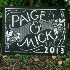 a black and white wedding sign sitting in the grass