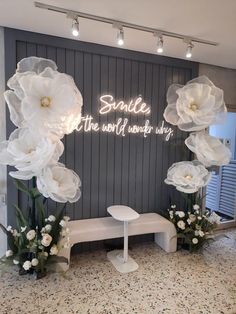 a white bench sitting in front of a wall with flowers on it and the words sandles the world wonderful day