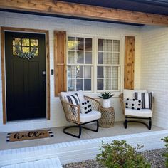 two wicker chairs sit on the front porch of a house with black and white accents