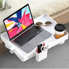 an open laptop computer sitting on top of a white desk next to a cup of coffee