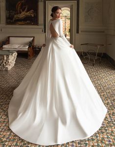 a woman in a white wedding dress standing in a room with paintings on the wall