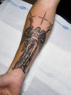 a person with a tattoo on their arm holding a cross and an angel above them