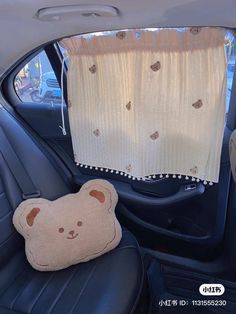 a teddy bear pillow sitting in the back seat of a car next to a window