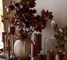 a table topped with lots of vases filled with flowers and candles next to each other