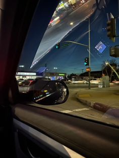 a car's rear view mirror is reflecting the city lights and traffic signal at night