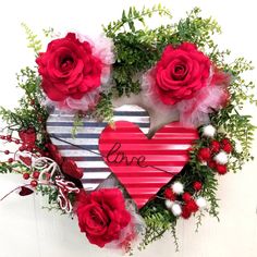 a heart shaped wreath with red roses and greenery