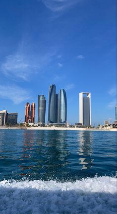 the city skyline is reflected in the water on a sunny day with blue skies and white clouds