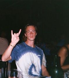 a man sitting at a table making the peace sign