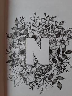 the letter n is surrounded by flowers and leaves on a white sheet with black ink