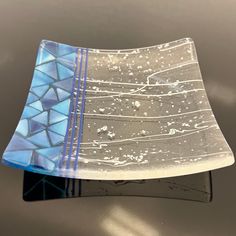 a blue and white glass plate sitting on top of a metal table next to a wall