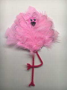 a pink feathered object with two faces on it's head and one eye