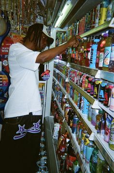 a woman is shopping in a store with canned drinks and sodas on the shelves