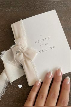 a woman's hand holding onto a letter to her husband with a bow on it