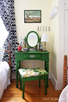 a green vanity table with a mirror and stool next to a window in a bedroom