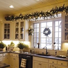 a kitchen decorated for christmas with wreaths and lights