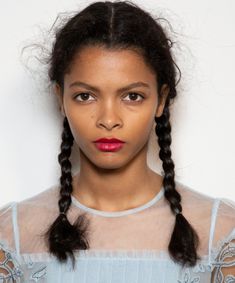 a woman with long black hair wearing a blue dress and braids on her head