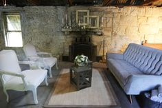 a living room filled with furniture and a fire place next to a stone wall covered in windows