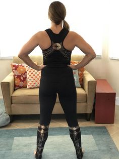 a woman standing in front of a couch with her back to the camera, wearing high heeled boots