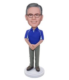 a bobble head man with glasses and a blue shirt standing on a white base