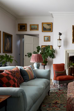 a living room with couches, chairs and paintings on the wall above them is shown