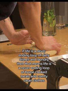 a person rolling dough on top of a wooden counter next to a glass filled with water