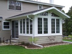 a house that has some windows on the side of it and grass in front of it