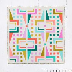 a quilted wall hanging on the side of a white wall with an abstract design