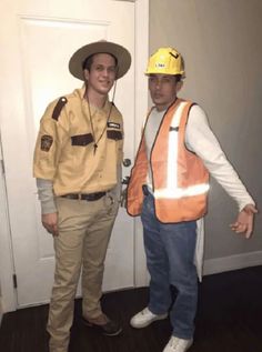 two men dressed in construction gear standing next to each other on the floor near a door