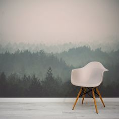 a white chair sitting in front of a wall with a forest mural on it's side