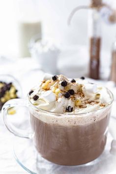 hot chocolate with whipped cream and black olives in a glass mug on a white table